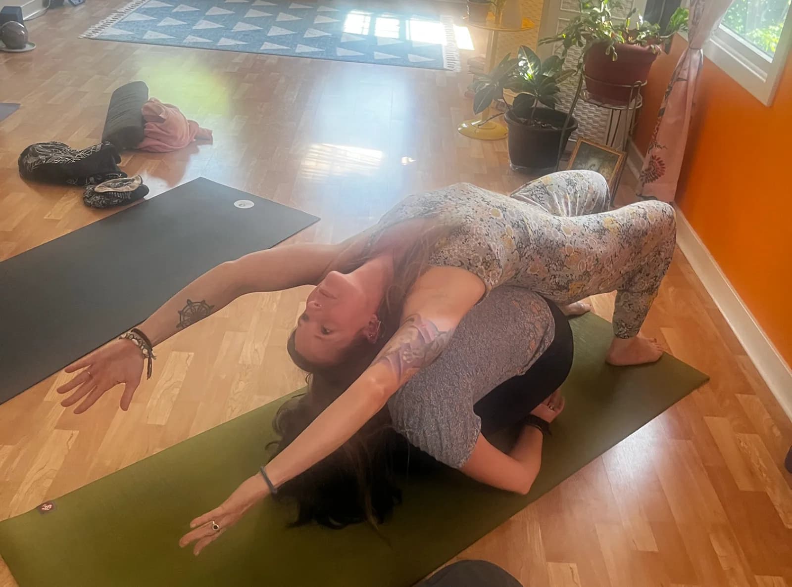 Jenn assisting a student in her yoga studio